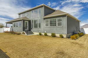 Back of house featuring a yard, cooling unit, stucco siding, and fence