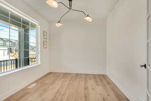 Unfurnished room with visible vents, baseboards, and light wood-style flooring
