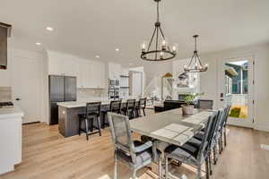 Dining area featuring recessed lighting, light wood-style floors, a glass covered fireplace, and stairs