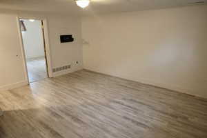 Spare room featuring visible vents, baseboards, and wood finished floors