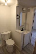 Bathroom featuring crown molding, baseboards, toilet, wood finished floors, and vanity