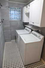 Laundry area featuring separate washer and dryer and cabinet space