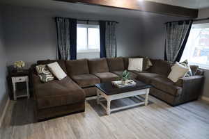 Living room with a wealth of natural light, beamed ceiling, and light wood finished floors