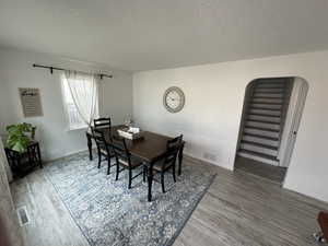 Dining area featuring visible vents, a textured ceiling, and wood finished floors