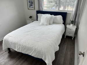 Bedroom featuring dark wood-type flooring and multiple windows