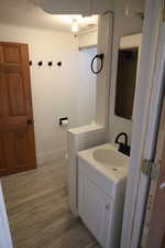 Bathroom featuring vanity, toilet, wood finished floors, and baseboards