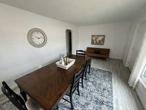 Dining room with baseboards, a textured ceiling, arched walkways, and wood finished floors