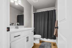 Full bathroom featuring visible vents, toilet, vanity, and wood finished floors