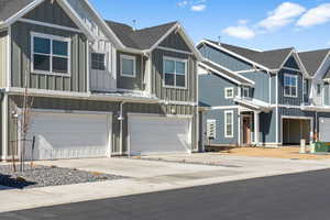 View of property featuring an attached garage, roof with shingles, board and batten siding, and driveway