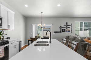 Kitchen with a chandelier, pendant lighting, light countertops, gas range oven, and a sink