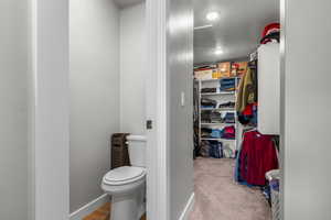 Bathroom with baseboards, toilet, a spacious closet, and a textured ceiling