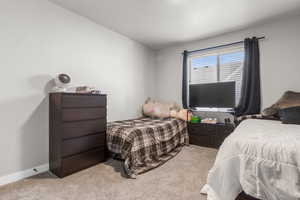 Bedroom with baseboards and light carpet