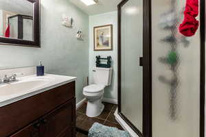Bathroom featuring baseboards, toilet, a stall shower, tile patterned floors, and vanity