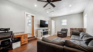 Living area featuring baseboards, dark wood-type flooring, a textured ceiling, and attic access
