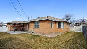Back of house featuring a gate, brick siding, a fenced backyard, and a patio area