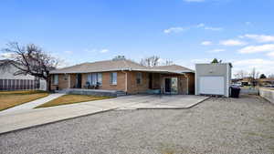 Ranch-style brick house with driveway, a front lawn, fence, a detached garage.