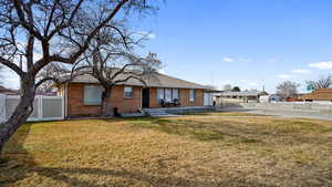 Ranch-style brick house with driveway, a front lawn, fence, a detached garage.