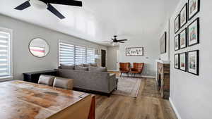 Dining space featuring a stone fireplace, wood finished floors, baseboards, and ceiling fans