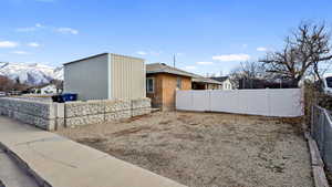 View of side of property featuring fence, brick siding, and a mountain view
