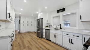 Remodeled Kitchen with LVP flooring, a sink, white cabinetry, recessed lighting, and stainless steel appliances