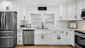 Remodeled dktchen featuring white cabinetry, quartz counters, appliances with stainless steel finishes, and a sink