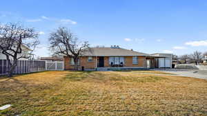 Ranch-style brick house with driveway, a front lawn, fence, a detached garage.