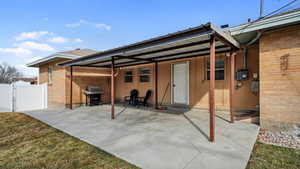Back of house featuring a patio, a gate, fence, and brick siding