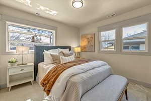 Bedroom featuring light carpet, visible vents, and baseboards