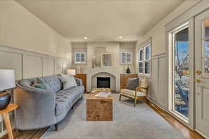 Living area featuring wood finished floors, recessed lighting, a fireplace, wainscoting, and a decorative wall