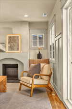 Living area with a wealth of natural light, a fireplace with flush hearth, visible vents, and wood finished floors