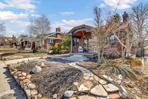 View of front of house with brick siding, a chimney, and fence