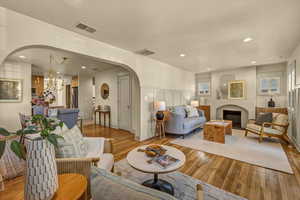 Living room with visible vents, arched walkways, and wood finished floors