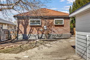 View of side of home featuring a tile roof, fence, and brick siding