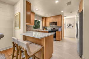 Kitchen featuring tasteful backsplash, visible vents, appliances with stainless steel finishes, and a peninsula