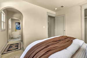 Bedroom featuring visible vents, arched walkways, baseboards, and carpet flooring