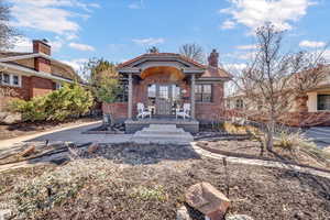 Back of property with a porch, french doors, brick siding, and a chimney