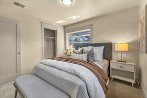 Carpeted bedroom featuring visible vents and a closet