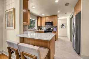 Kitchen featuring visible vents, appliances with stainless steel finishes, a peninsula, and decorative backsplash