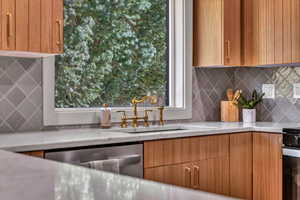 Kitchen featuring a sink, stove, dishwasher, modern cabinets, and tasteful backsplash