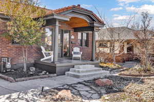 Property entrance featuring brick siding, a porch, and a tile roof