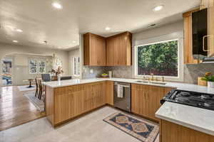 Kitchen featuring visible vents, a peninsula, arched walkways, a sink, and stainless steel dishwasher