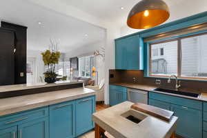 Kitchen with a sink, backsplash, blue cabinetry, and stainless steel dishwasher