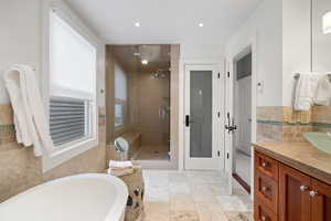 Full bathroom with vanity, recessed lighting, a tub, decorative backsplash, and a shower stall