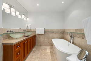 Bathroom featuring a sink, a freestanding tub, recessed lighting, and double vanity