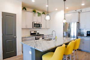 Kitchen with a breakfast bar, deep sink, decorative light fixtures, granite countertops, soft closing cabinets, stainless steel appliances, and light wood-style floors, 9 foot ceilings