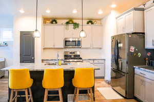 Kitchen with a breakfast bar, deep sink, decorative light fixtures, granite countertops, stainless steel appliances, and light wood-style floors, 9 foot ceilings