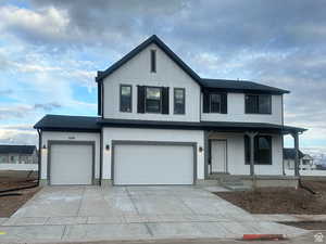 Modern farmhouse with covered porch, concrete driveway, and a garage