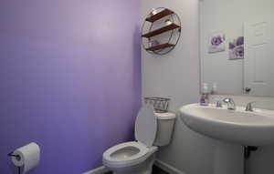 Bathroom with toilet, baseboards, and a sink