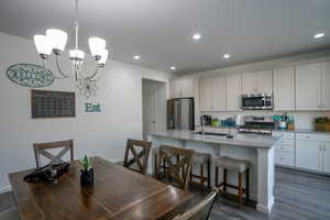 Kitchen featuring backsplash, a center island with sink, a kitchen bar, stainless steel appliances, and a sink