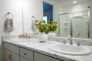 Bathroom featuring double vanity, a shower with shower door, and a sink